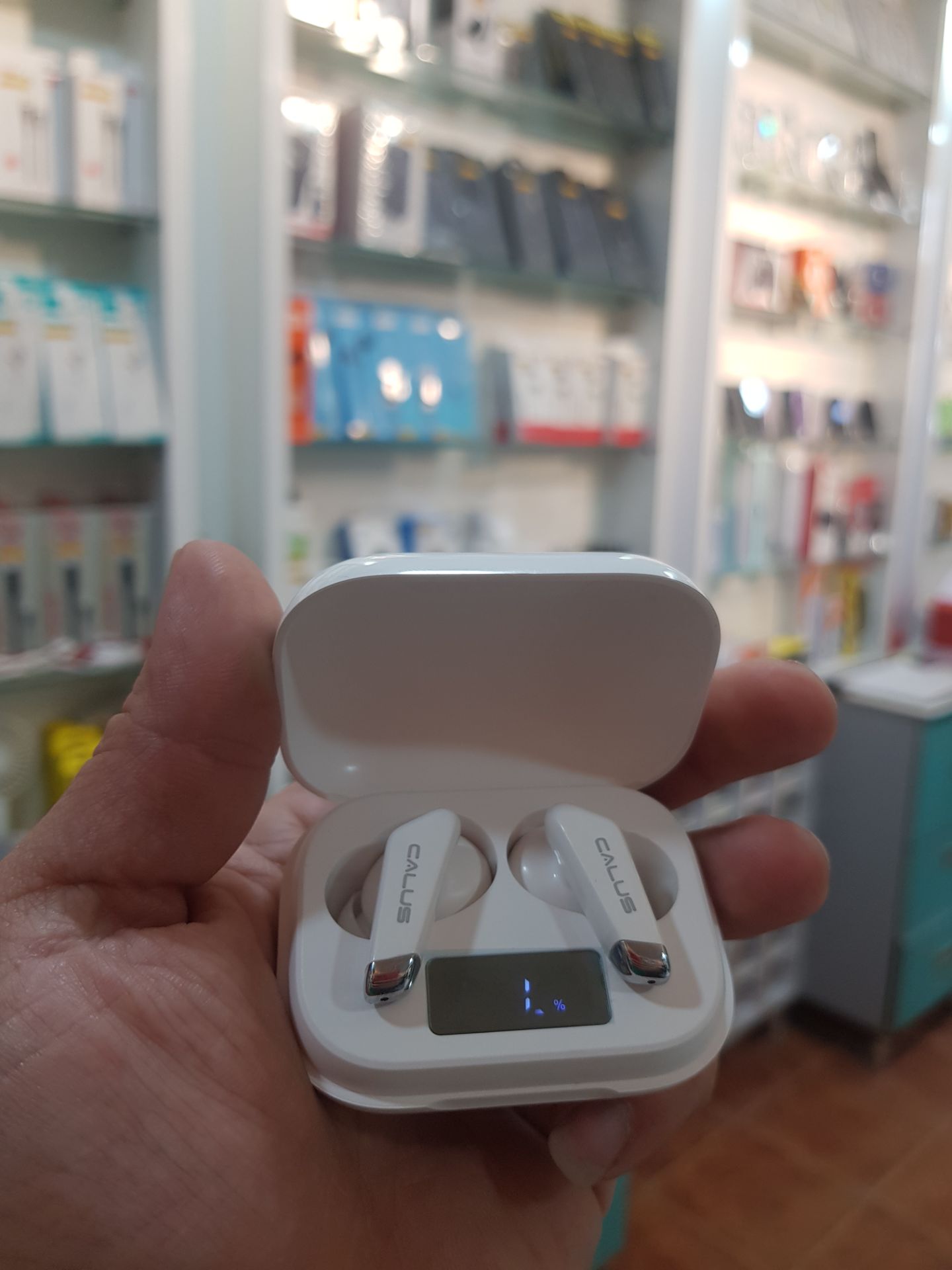 نگاه نزدیک به داخل کیس شارژ ایرپاد کالوس مدل C7 Pro همراه با گوشی‌ها در فروشگاه مُجیتِل