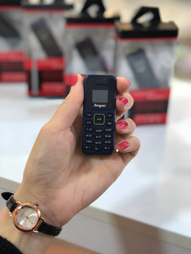 گوشی مینی هوپ مدل L666 در دست یک نفر، نمایش اندازه بسیار کوچک و صفحهکلید گوشی در فروشگاه لوازم جانبی موبایل.