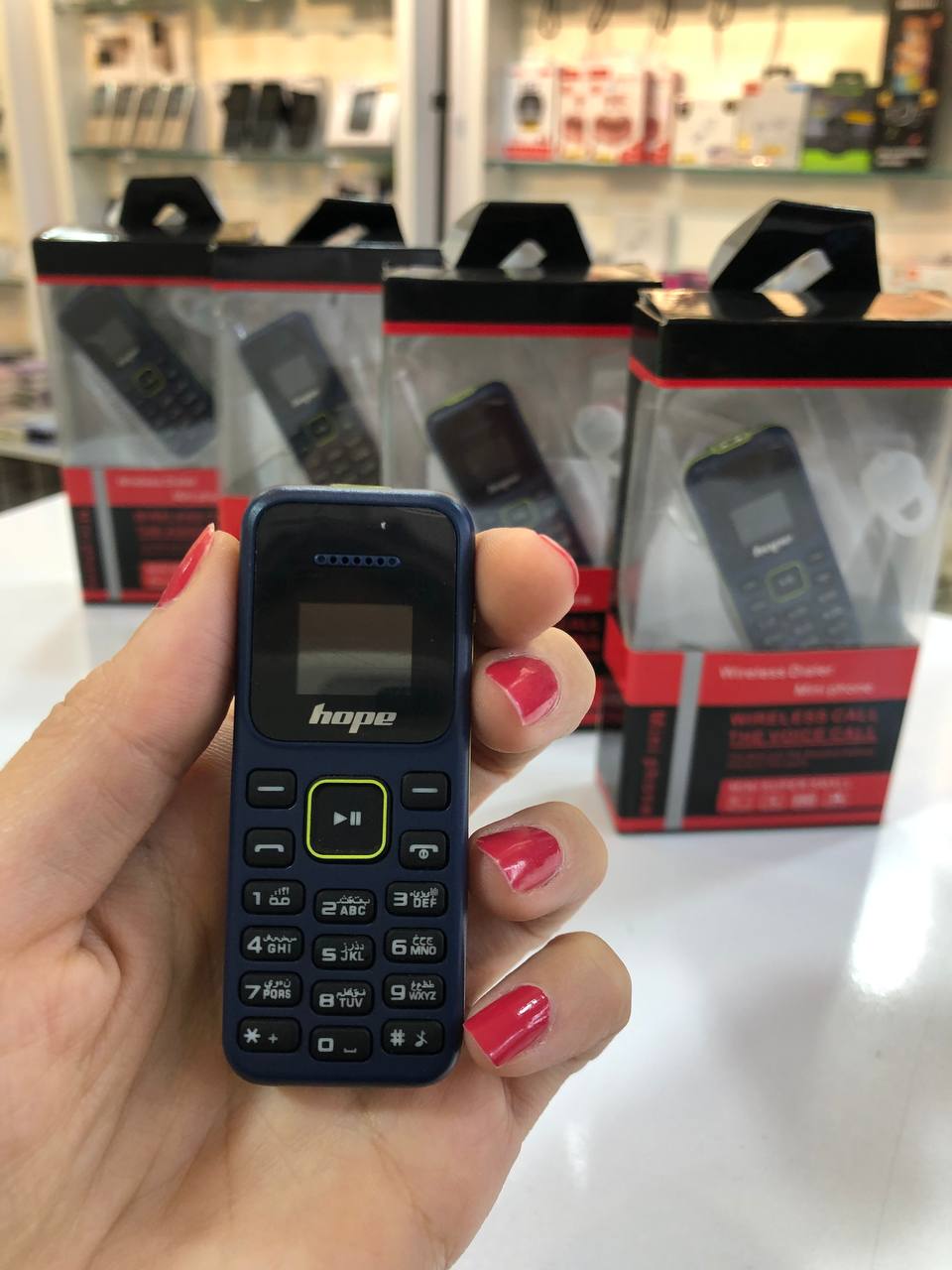 گوشی مینی هوپ مدل L666 همراه با جعبه و لوازم جانبی روی پیشخوان سفید در فروشگاه موبایل.