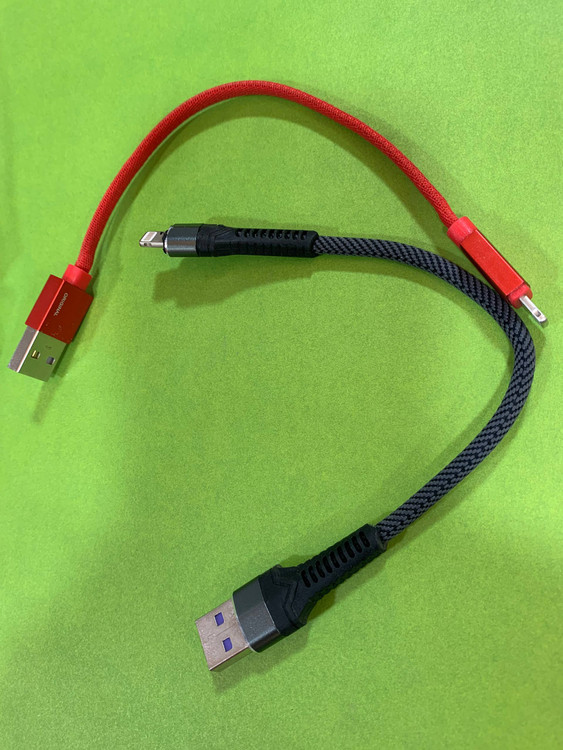 Short red Lightning power bank cable on green background