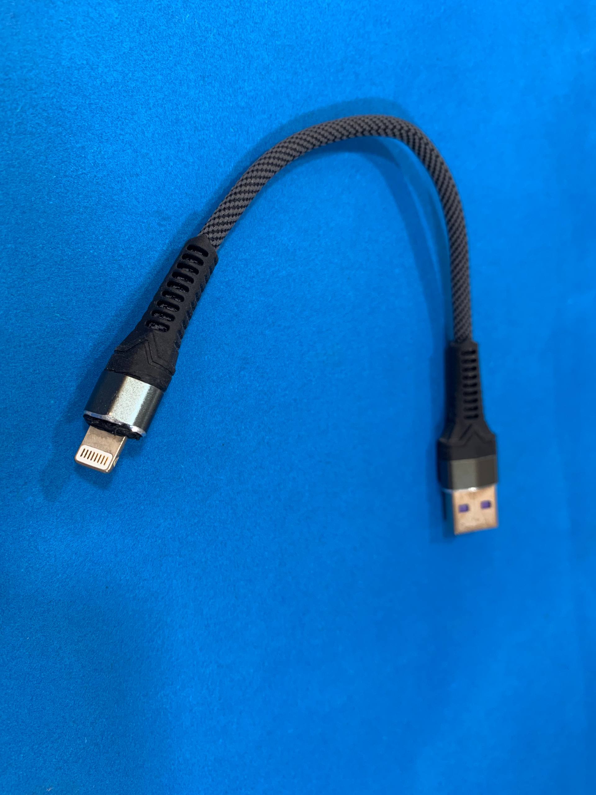 Black short Lightning charging cable with USB connector on blue background